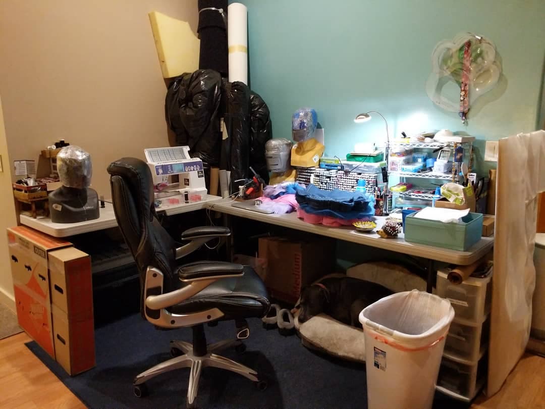 The sewing corner — machine, fabric, and the workshop dog asleep under the desk